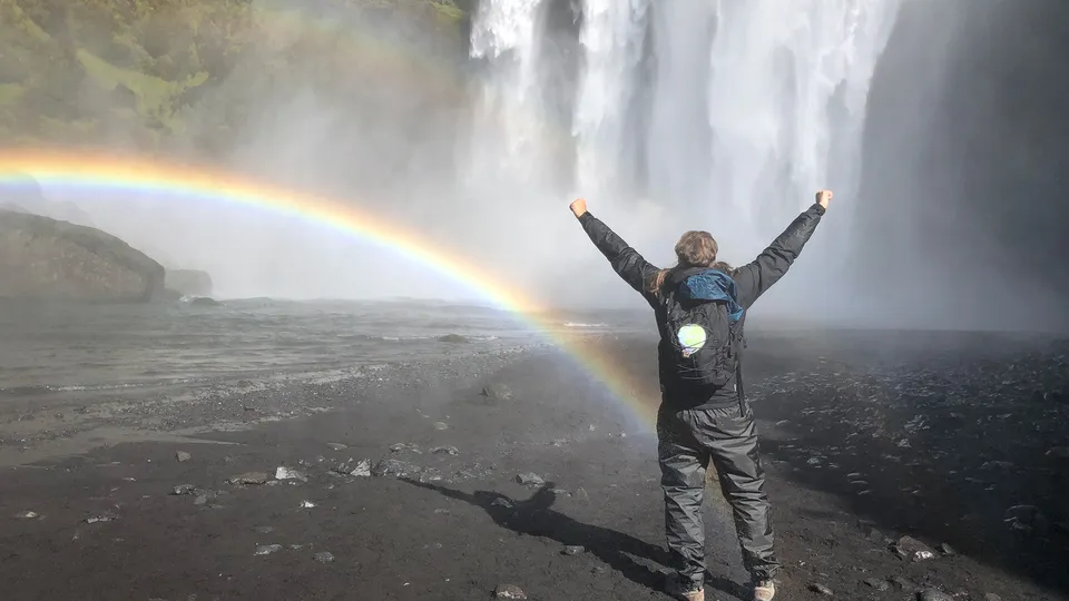 Uomo con braccia alzate di fonte alla cascata di Skogafoss in Islanda