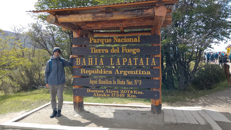 Uomo vicino al cartello di ingresso del Parco Nazionale della Terra del Fuoco