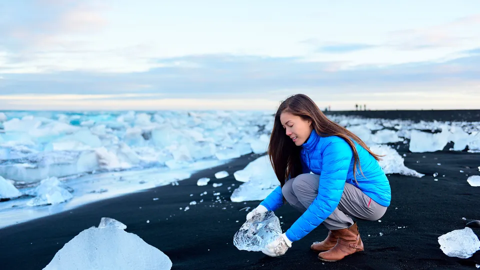 Donna che raccoglie frammenti di iceberg sulla Diamond Beach in Islanda
